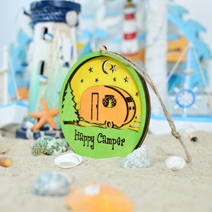 Detail of wooden Happy Camper wall sign with layered forest and caravan design