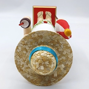 Top view of wooden Santa nutcracker with straw hat, coconut drink and beach umbrella