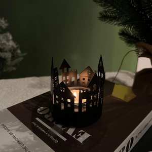 Detail of black Nordic house silhouette candle holder with tea light on book