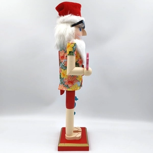 Side view of a wooden Santa nutcracker wearing a tropical Hawaiian floral shirt and sunglasses