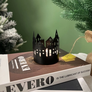 Close-up of black metal Nordic house candle holder with warm tea light on books