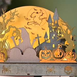 Detail of wooden Halloween LED light featuring a castle, witch, and warm BOO lettering