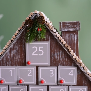 Gray wooden 25-day Christmas countdown calendar house with festive pine and berry decor