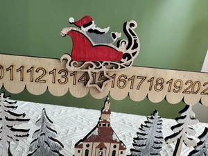 Macro shot of wooden Christmas advent calendar with Santa sleigh and church details