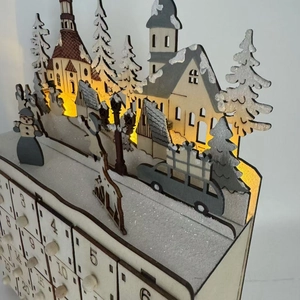 Macro view of wooden advent calendar with LED lighted winter village and numbered drawers