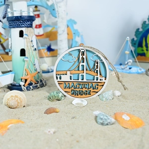 Detail of multi-layered wooden Mackinac Bridge ornament on sand with sea shells