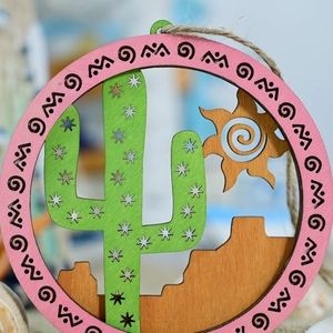 Detail of wooden round ornament featuring desert cactus and tribal geometric patterns