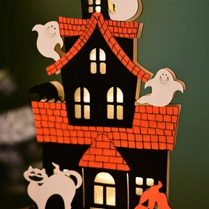 Detail of wooden Halloween house lamp with warm LED lights and ghost silhouettes