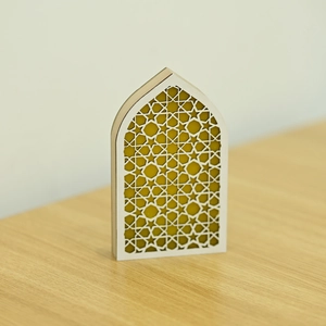 Detail of white arched Muslim LED ornament with golden geometric star patterns on wood