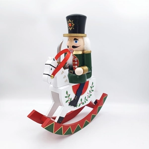 Detail of hand-painted wooden nutcracker soldier on white rocking horse decor