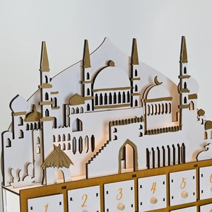 Nahaufnahme vom Ramadan-Countdown-Kalender aus Holz mit goldener Moschee-Silhouette und Schubladen