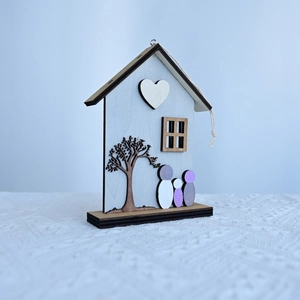 Detail of wooden house ornament with heart tree motifs and warm family silhouettes