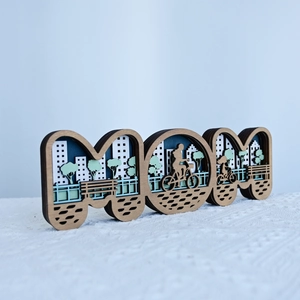 Détail de la sculpture MOM en bois 3D avec silhouettes de ville découpées au laser
