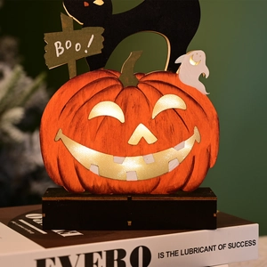 Detail of wooden Halloween pumpkin lamp with glowing face, black cat, and ghost decor