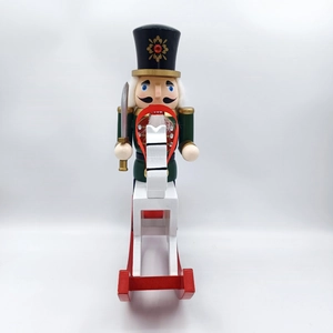 Detail of traditional green nutcracker soldier on white rocking horse Christmas ornament