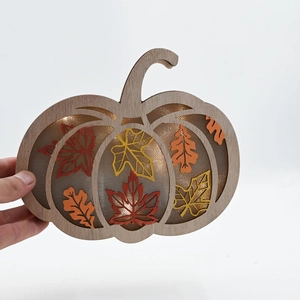 Macro detail of pumpkin shaped wooden LED light with autumn maple leaf patterns