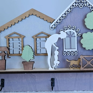 Detail of laser-cut wooden house ornament with mother and child silhouettes and hooks