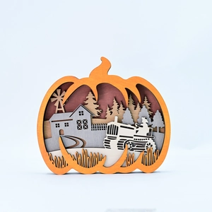 Detail of multi-layer wood pumpkin carving featuring a farm landscape with a tractor
