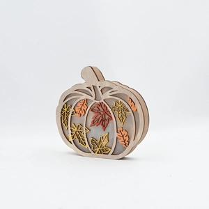 Macro shot of a layered wooden pumpkin decor with colorful maple leaf cutouts inside
