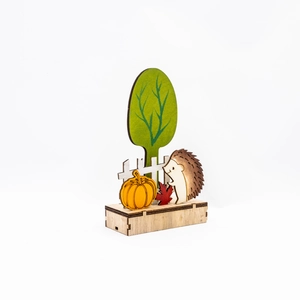 Dettaglio decorazione autunnale in legno con zucca, riccio e foglie di acero rosse