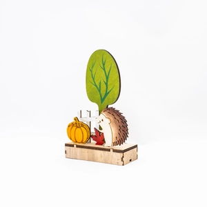 Dettaglio macro decorazione autunnale in legno con riccio, zucca e albero verde