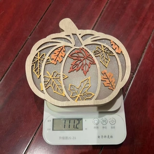 Hollow pumpkin wooden ornament with autumn maple leaves shown weighing 111.2g on a scale