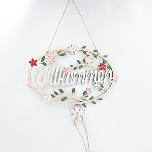 Close-up of wooden Willkommen sign with painted flowers and bird for home wall decor
