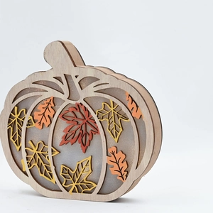 Detail of wooden pumpkin decor with layered maple leaves and warm autumn colors