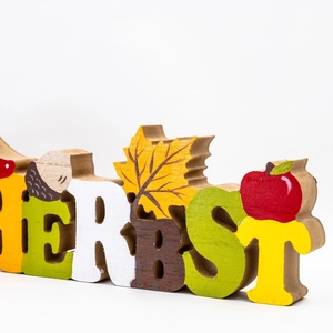 Macro side view of wooden 'HERBST' autumn letters with acorn and maple leaf motifs