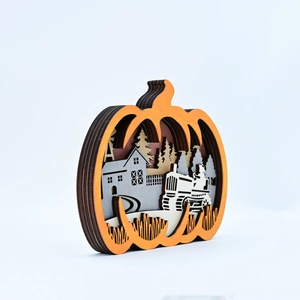 Detail of multi-layered wooden pumpkin ornament with a carved countryside farm scenery