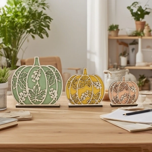 Three wooden pumpkin ornaments with maple leaf laser-cut details on a black stand