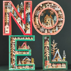 Detailed laser-cut NOEL wood ornaments with miniature winter scene layers and LED lights