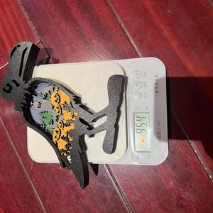 Detailed weight display of multi-layer wood raven Halloween ornament on a digital scale