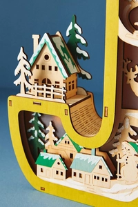 Detailed view of yellow Christmas wooden letter light with multilayer miniature snow scene