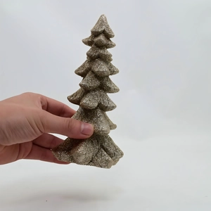 Close-up of golden glitter Christmas tree resin ornament held in hand for size reference