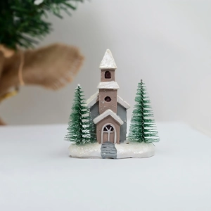 Detail of miniature resin Christmas church with snow-covered base and small pine trees