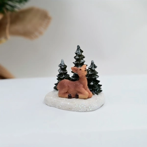 Détail d'une figurine de renne de Noël en résine avec sapins sur socle enneigé