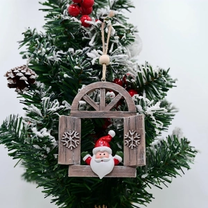 Detail of resin Santa Claus pendant hanging on snowy branch with rustic twine and wood bead
