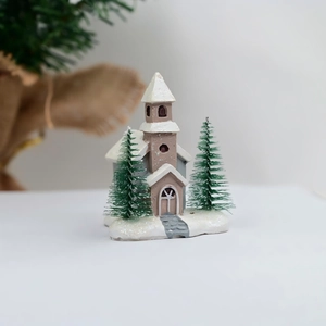 Close-up of resin Christmas church miniature with snow-dusted trees and silver glitter finish