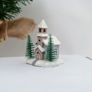 Close-up of resin Christmas church miniature with snow roof and tiny pine trees
