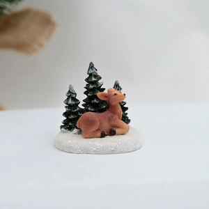Détail d'une figurine de renne de Noël en résine avec sapins enneigés sur base pailletée