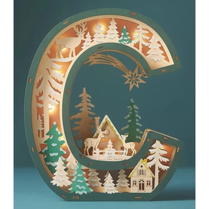 Detail of wooden letter C LED light with layered forest reindeer and cozy cabin scene