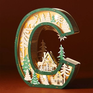 Detail of wooden letter C LED lamp with laser-cut forest landscape and reindeer scenery
