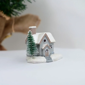 Detail of miniature resin Christmas snow house with snow-covered roof and tiny pine tree