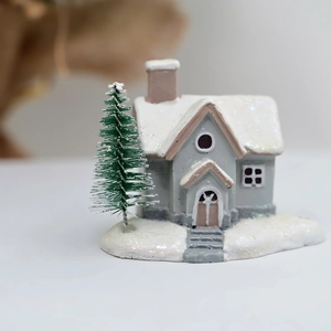 Macro view of a resin Christmas snow house miniature with a frosted pine tree