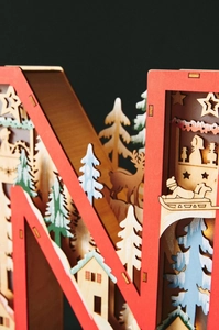 Detail of wooden LED Christmas letter light featuring laser-cut winter forest scenes