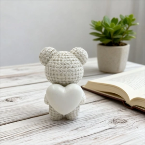 Handmade knitted teddy bear holding white resin heart for desk decor and healing room aesthetic