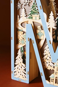 Close-up of laser-cut wooden Christmas LED letter light with snow and bear details