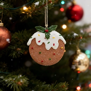 Close-up of a Christmas pudding tree ornament with white icing and holly leaf details