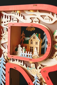 Detailed macro view of 3D multi-layered wooden LED Christmas ornament with snowy forest scene